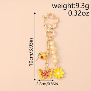 Detailed view of floral keychain with enamel butterfly, cherry charm and pearl beads