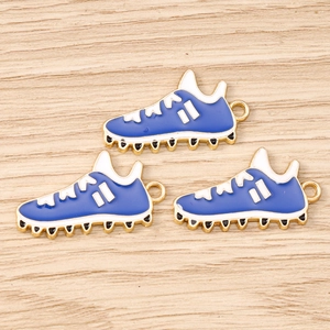 Detailansicht der blauen Fußballschuh-Anhänger mit goldenem Rand auf Holzgrund