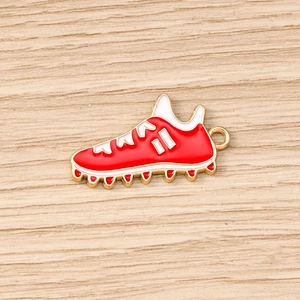 Makroaufnahme der rot-weißen Emaille-Fußballschuh-Anhänger auf hellem Holz-Hintergrund
