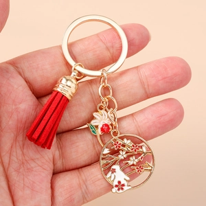 Detailed close-up of a Chinese style gold keychain featuring a red tassel and rabbit charm