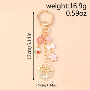 Detail of pink daisy and white bow charms on a gold hollow wreath keychain with size labels