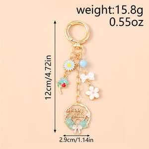 Detail of floral keychain with daisy, bow, and cherry blossom showing 12cm length and weight