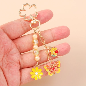 Golden keychain with cherry blossom clasp, yellow daisy, red flower and butterfly charms
