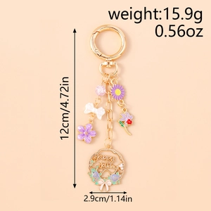 Detail of floral keychain with Happy Holiday engraving, purple flower and white bow charm