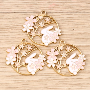 Detail of three gold floral bunny wreath charms with pink enamel for DIY jewelry making