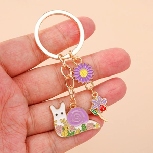 Enamel snail keychain with purple shell and small floral charms in gold plating