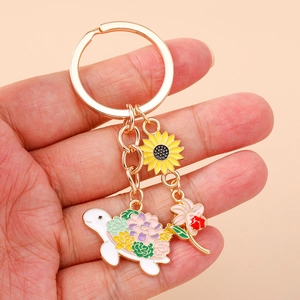 Golden keychain with cute white turtle featuring floral shell and sunflower charm detail