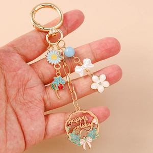 Floral Happy Holidays gold keychain with blue sunflower, bow, and pearl bead charms
