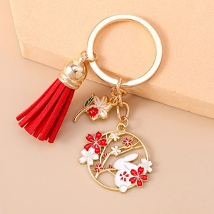 Detailed shot of rabbit and cherry blossom keychain with red tassel on gold ring