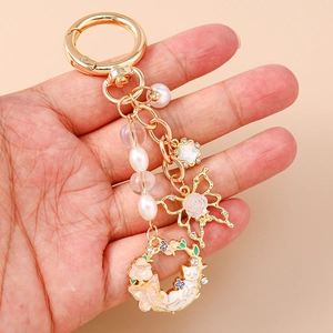 Elegant gold keychain with pearls, pink rose butterfly, and cat floral wreath charm