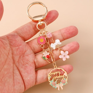 Floral keychain with Happy Holidays wreath, pink sunflower, and bow pendant on golden ring