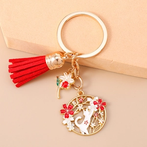 Detail of a Japanese-style cat and cherry blossom keychain with red tassel and gold ring