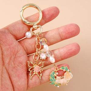 Elegant gold butterfly and cat wreath keychain with pearls and pink floral charms