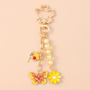 Detail of gold keychain with cherry blossom clasp, enamel butterfly and flower charms