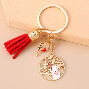 Detailed close-up of a golden cat and cherry blossom keychain with red tassels
