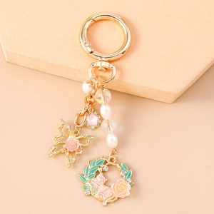 Detail of golden butterfly keychain with pink rose star and pearl beads charm