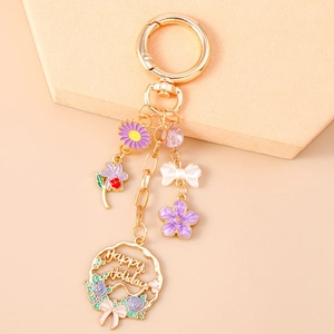 Detailed close-up of a gold floral keychain with Happy Holidays engraving and enamel charms