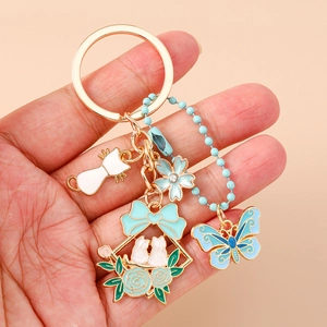 Dettaglio di ciondoli in smalto con coniglio, fiore e farfalla su un portachiavi dorato