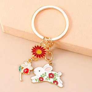 Detailed close-up of gold enamel keychain with rabbit, sunflower and white flower charms