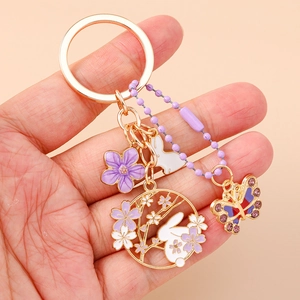 Dettaglio del portachiavi con coniglio e fiori in smalto viola e finitura oro rosa