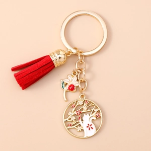 Detailed close-up of a golden cat keychain with red leather tassel and cherry blossoms