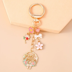 Detail of floral keychain with pink flower, bow charm and Happy Holidays gold pendant