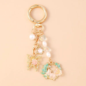 Close-up of pink cat wreath keychain with butterfly, pearls, and star charms in gold finish