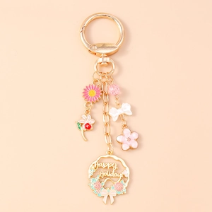 Detailed view of golden flower keychain with pink sunflowers and Happy Holidays charm