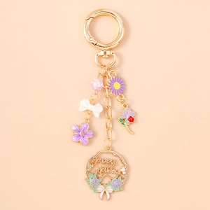 Detailed view of golden keychain with purple flower, white bow and Happy Holiday charm