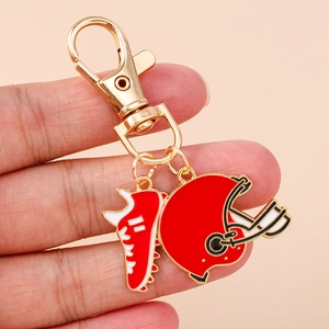 Rugby theme keychain with red helmet and football shoe charms on a golden clasp