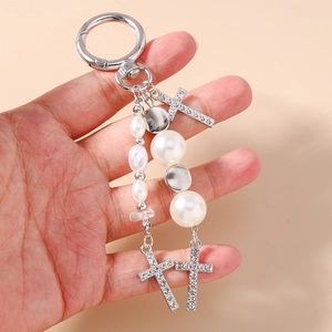 Silver pearl keychain with cross pendants and diamond accents held in hand