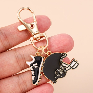 Golden keychain with black football helmet and soccer shoe pendants held in hand