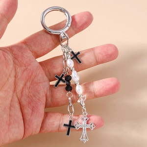 Handheld display of silver cross keychain with black charms and elegant white pearls