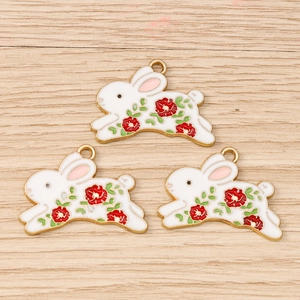 Detailed macro view of three enamel bunny pendants with red flower and gold metal edges