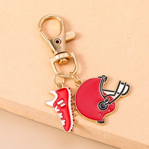 Detailed close-up of a red rugby helmet and sneaker keychain with gold-tone hardware