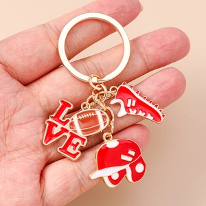 Rugby sports keychain featuring red helmet and love charms on a gold ring held in palm