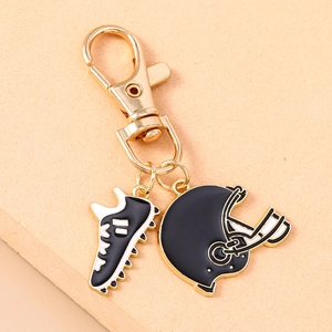 Detailed close-up of golden keychain featuring black and white football shoe and helmet pendants
