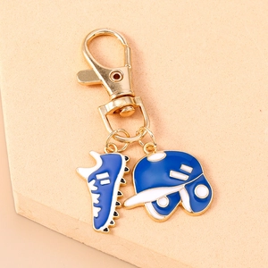 Detail of a golden carabiner keychain with navy blue enamel baseball shoe and helmet charms