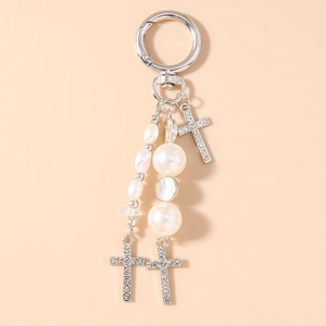 Detail of silver cross pendant keychain with sparkling rhinestones and white pearls