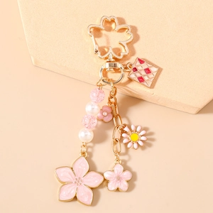 Detail of pink cherry blossom keychain with gold alloy carabiner and faux pearl charm
