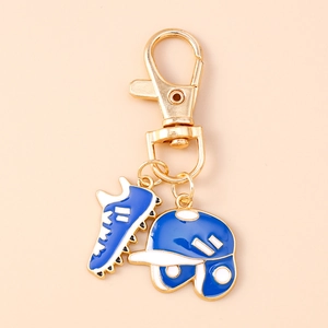 Close-up of blue enamel baseball helmet and sneaker charms on a gold keychain