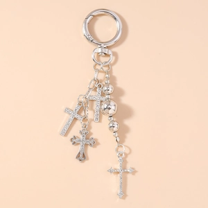 Detailed macro view of silver cross pendants with pearls and rhinestones on a keychain