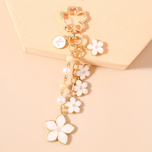 Detail of cherry blossom keychain with letter K charm and white enamel flowers on gold base