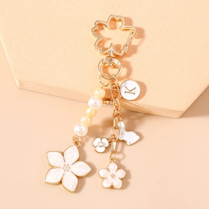 Detail of cherry blossom keychain with letter K charm, white rabbit and pearl chain