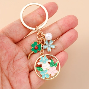 Gros plan détaillé d'un porte-clés doré avec motifs floraux, un lapin blanc et une perle