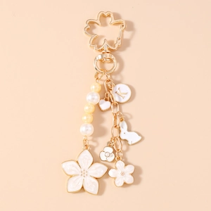 Detail of cherry blossom keychain with gold enamel petals, pearls and a letter K charm