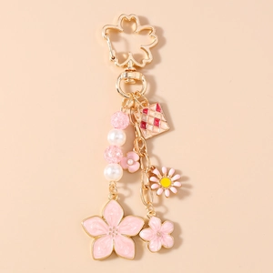 Close-up of pink enamel cherry blossom and daisy charms on a gold-tone keychain