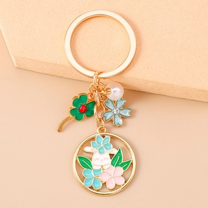 Détails d'un porte-clés couronne de lapin doré avec fleurs émaillées et perles