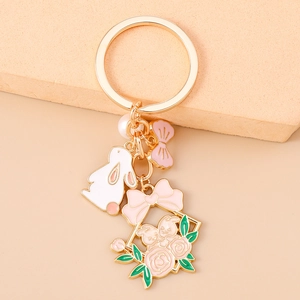 Vue macro d'un porte-clés doré avec des breloques lapin rose, perle et motifs floraux