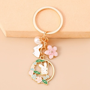 Détail de porte-clés lapin avec des fleurs de cerisier et perles blanches